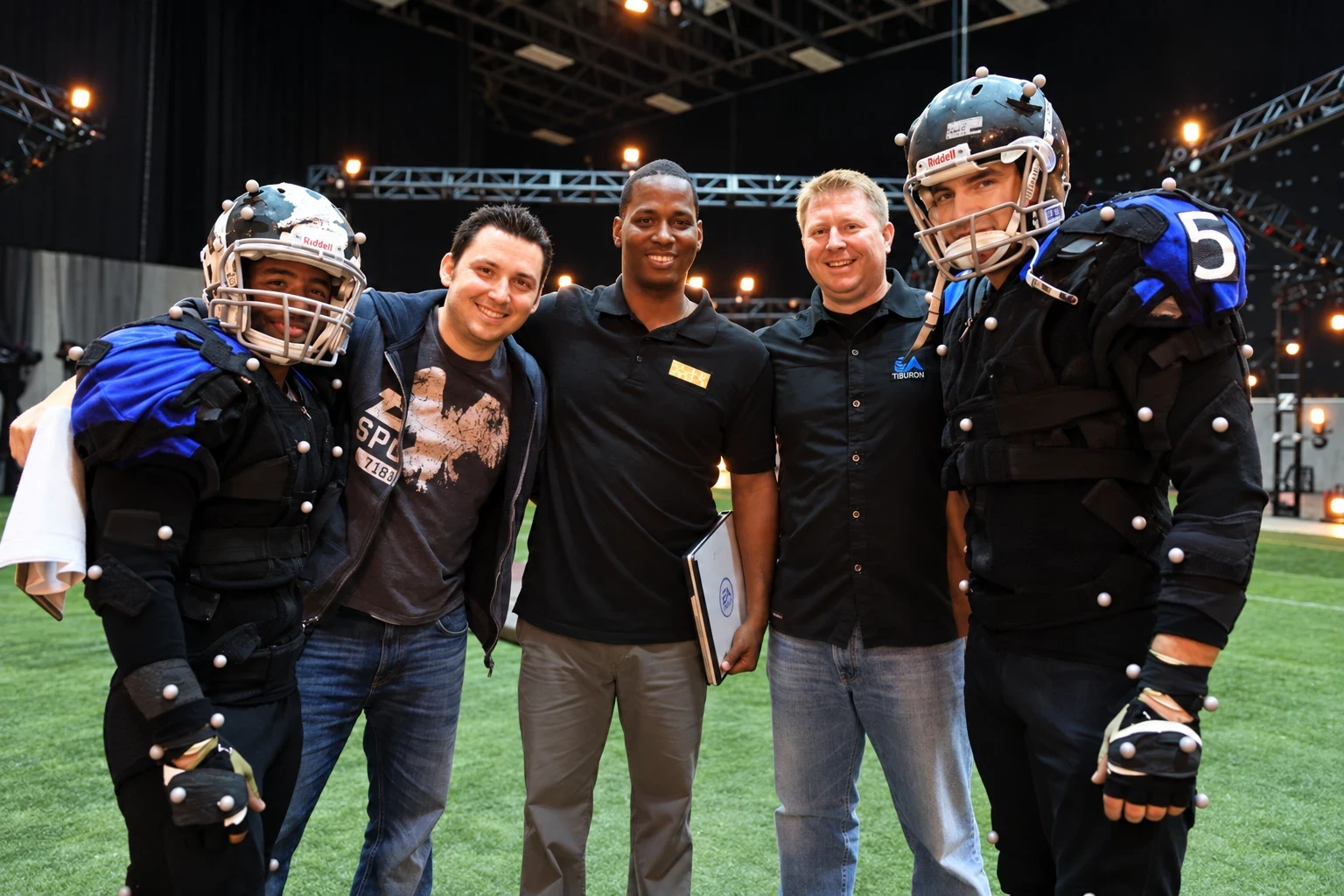 Sean Diehl with colleagues and two athletes in mocap suits and helmets on a motion capture stage