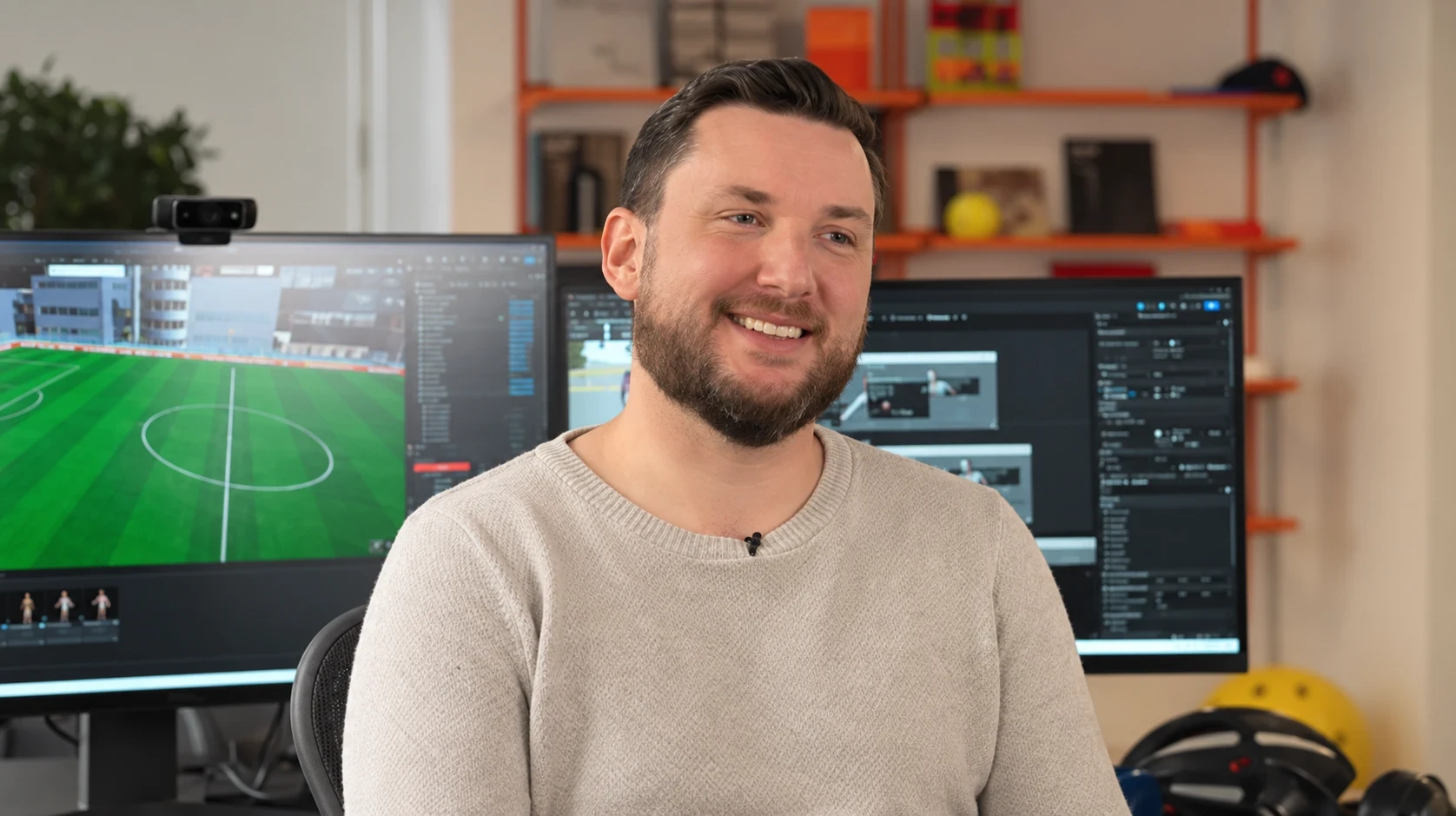 Sean Diehl smiling at his desk, with Unreal Engine and GOALS gameplay on the monitors behind him